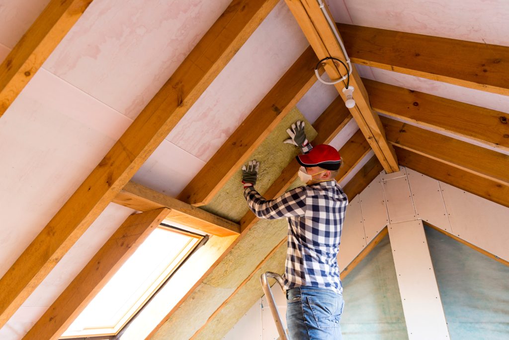 Man installing thermal roof insulation layer - using mineral wo This is a picture for a blog about what insulation contractors do.